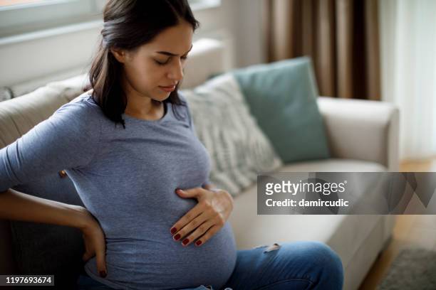 young pregnant woman suffering from backache - symptom stock pictures, royalty-free photos & images