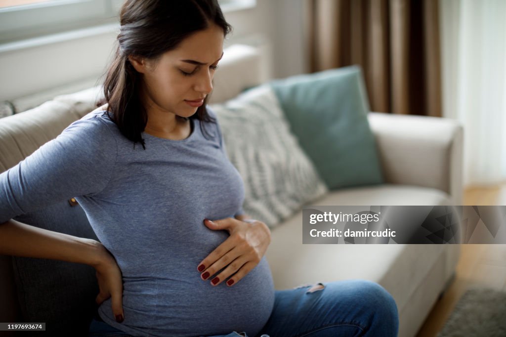 Mulher gravida nova que sofre da dor nas costas