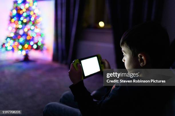 boy gaming at home on portable games console - bluetooth stock-fotos und bilder