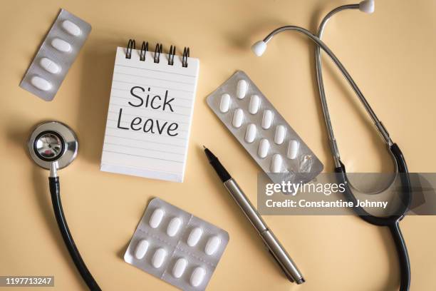 sick leave written on notebook with pill blister packs and stethoscope - krankenstand stock-fotos und bilder