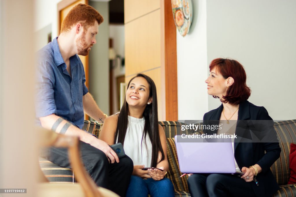 Woman explaining investiment plan to a couple, in the living room