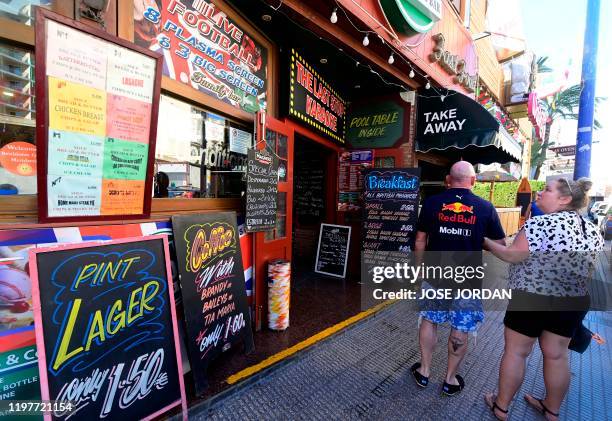 People walk along a commercial street full of British businesses in Benidorm on January 31, 2020. - On the sun-drenched eastern coast of Spain,...