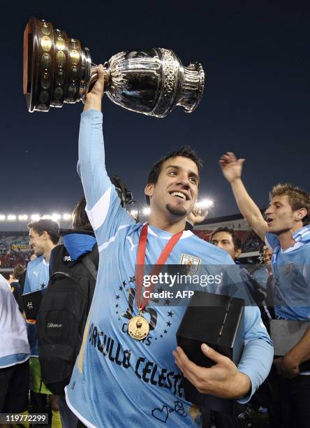 Uruguayan defender Mauricio Victorino raises the trophy and celebrates with teammates at the end of the 2011 Copa America football tournament final...
