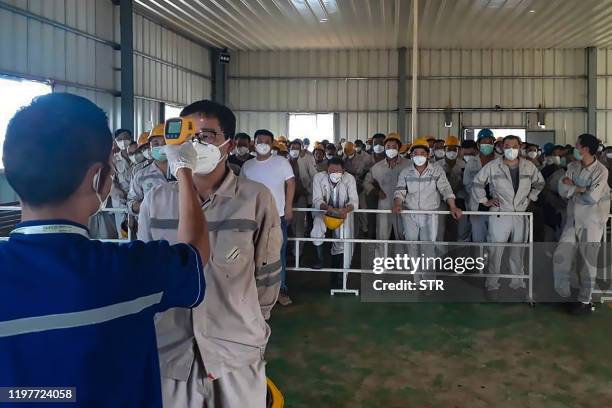 This photograph taken on January 30, 2020 shows a health official checking the body temperature of a worker at PT Indonesia Morowali Industrial Park...