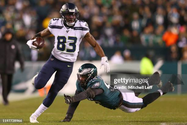 David Moore of the Seattle Seahawks carries the ball against Derek Barnett of the Philadelphia Eagles during the NFC Wild Card Playoff game at...