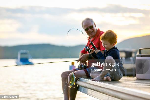 grandfather and grandson fishing at sunset in summer - lake fishing stock pictures, royalty-free photos & images