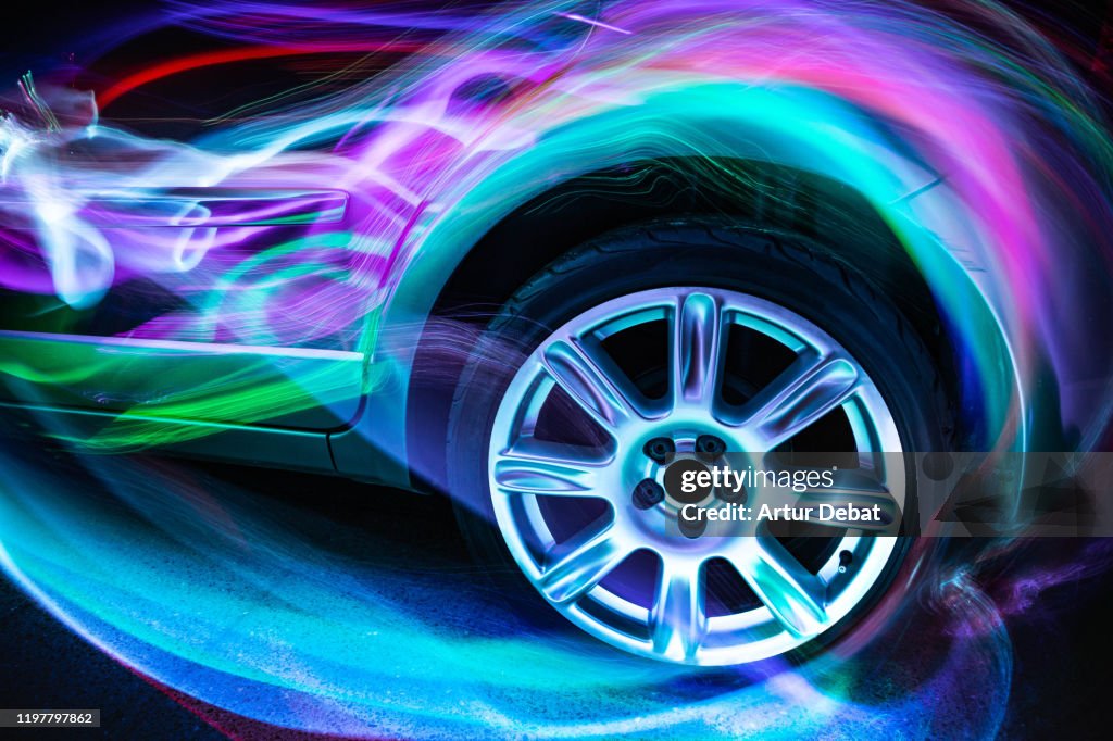 Colorful aerodynamic light trails playing with the car shape at night.