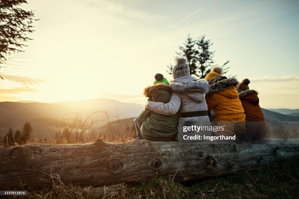 Mother and kids enjoying sunset in mountains