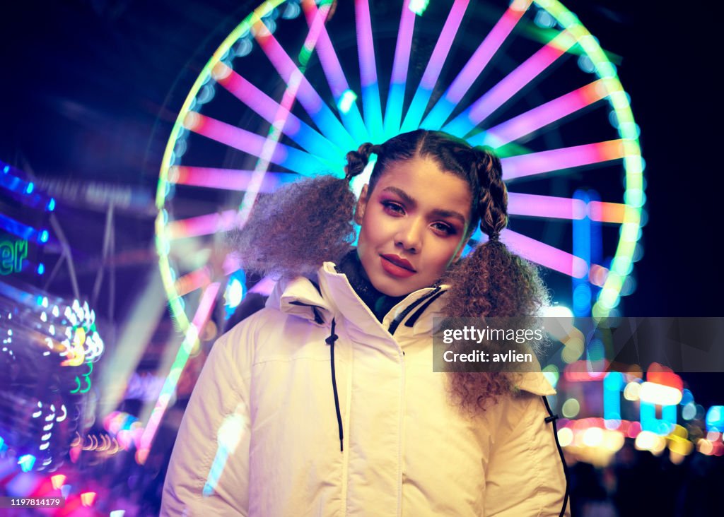 Portrait Of Smiling Woman Standing Against Illuminated Ferris Wheel At Night