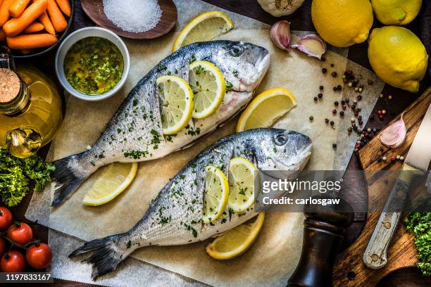レモン、パセリ、ニンニクで魚肉を調理 - ワックスペーパー ストックフォトと画像