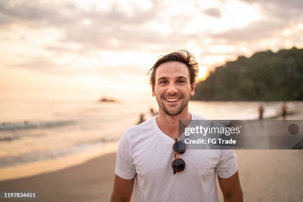 portret van mannen die glimlachen op het strand - beach man stockfoto's en -beelden