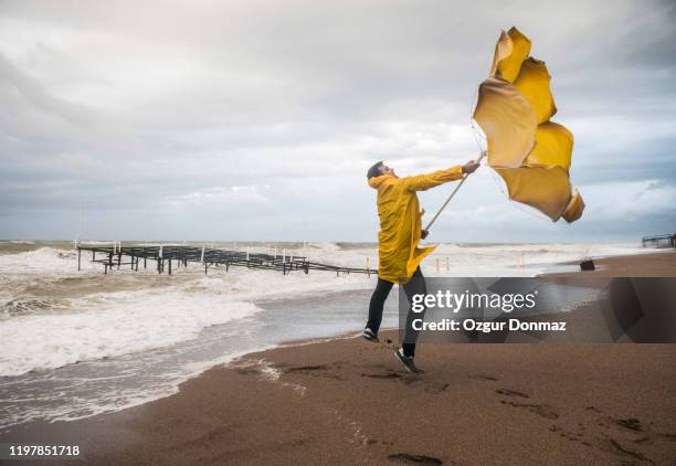 man struggling with umbrella on windy beach, antalya, turkey - broken umbrella stockfoto's en -beelden