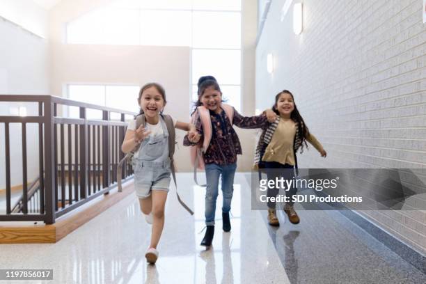 three schoolgirls running in school hallway - child running up stairs stock pictures, royalty-free photos & images