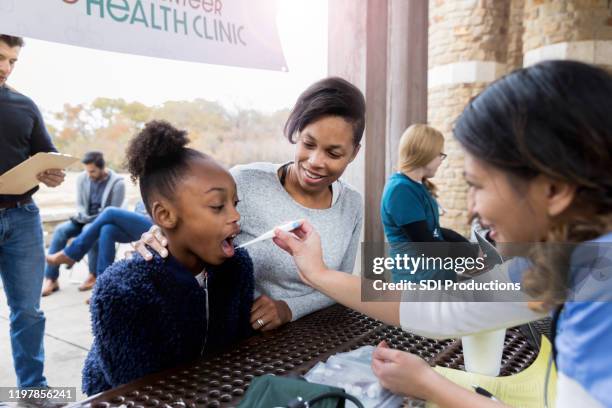 mensen wachten in de rij als verpleegkundige neemt kinder temperatuur - gratis stockfoto's en -beelden