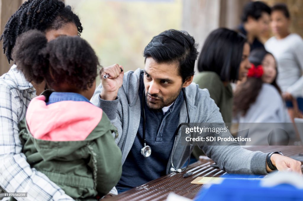 Doctor checks child's eyes with light at free clinic