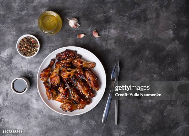 spicy chicken wings with teriyaki sauce and sesame seeds in a white plate on a dark background.top view, copy space. - plate food photos et images de collection