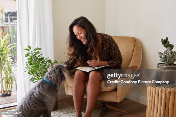 laughing mature woman relaxing with her dog at home - hawaiian women weaving stock pictures, royalty-free photos & images