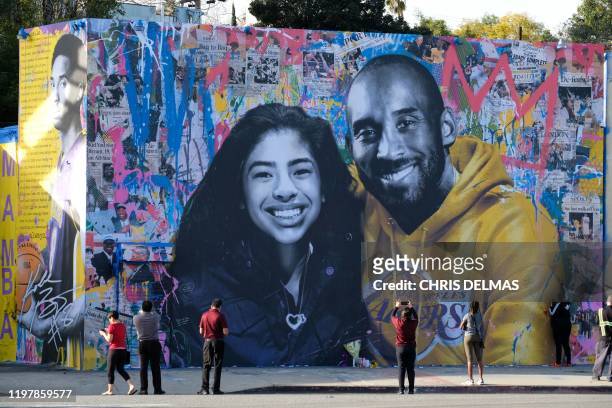 People stop to take pictures in front of the new mural by French artist Mr. Brainwash picturing Kobe Bryant and his daughter Gigi in Los Angeles on...