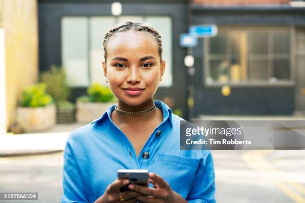 woman looking at camera with smart phone - female body piercing stock pictures, royalty-free photos & images