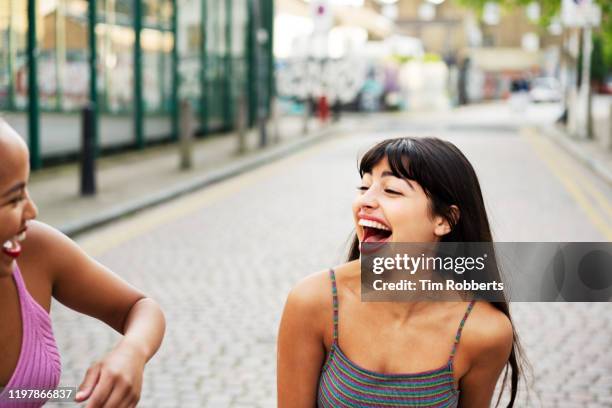 two women laughing together in city - attitude youthful asian stock-fotos und bilder
