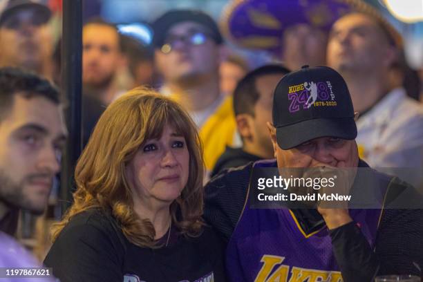 People watch a pre-game tribute to Kobe Bryant on televisions in a restaurant near Staples Center as the first Lakers game since the former NBA star...