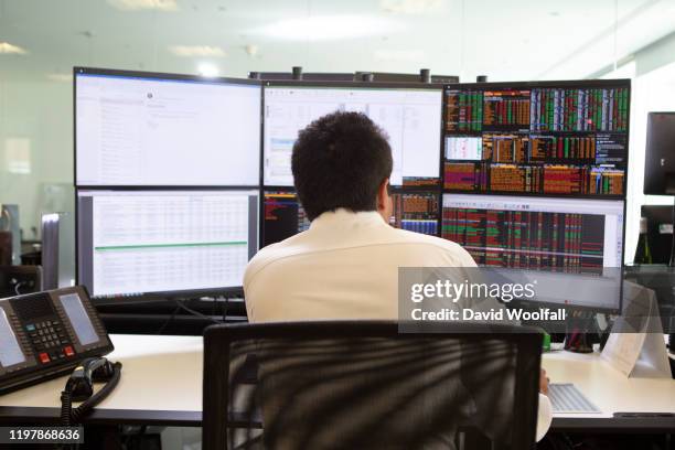 stock trader looking at screens - börsensaal stock-fotos und bilder