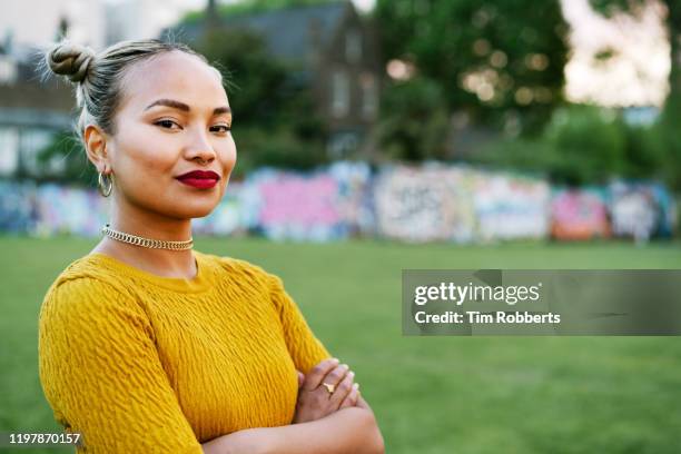 portrait of confident woman in city park - stolz stock-fotos und bilder