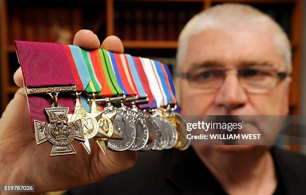 Rob Kenna holds up the Victoria Cross medal awarded to his father Ted Kenna for bravery during action against the Japanese in New Guinea, and which...