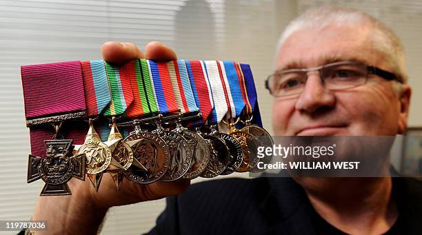 Rob Kenna holds up the Victoria Cross medal awarded to his father Ted Kenna for bravery during action against the Japanese in New Guinea, and which...