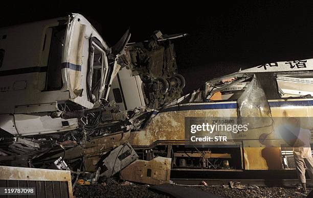 This photo taken on July 24, 2011 shows a rescuer working on a mangled carriage after a Chinese high-speed train derailed when it was hit from behind...