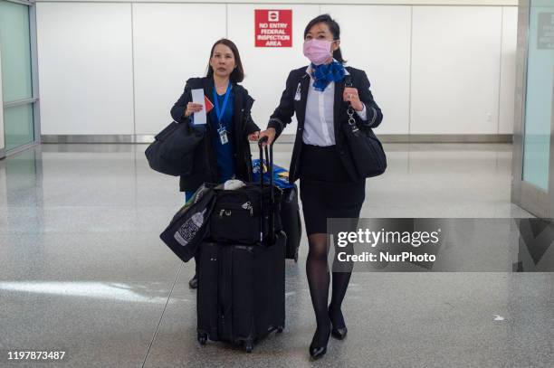 United Airlines flight attendant wearing face masks walks out of the international terminal at the San Francisco International Airport in Millbrae,...