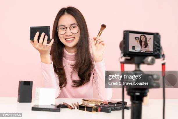 asian woman professional beauty vlogger or blogger live broadcasting cosmetic makeup tutorial viral video clip by camera sharing on social media. business online influencer on social media concept. online selling. online shopping - tutorial stock-fotos und bilder