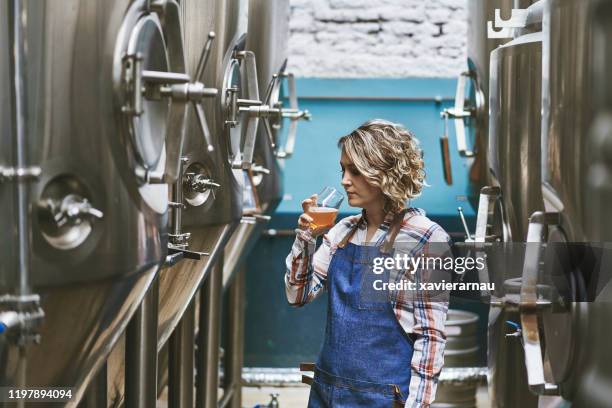 hispanic vrouwelijke ambachtelijke brouwer onderzoek bier monster - brouwerij stockfoto's en -beelden