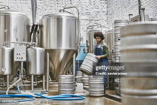 young native american brewery worker stacking beer kegs - vat stock pictures, royalty-free photos & images