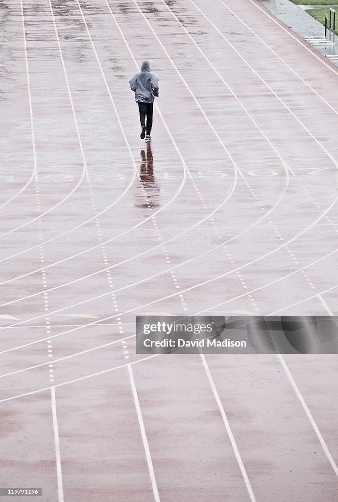 Man running on track in the rain.