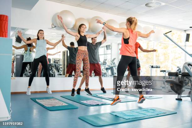 multi ethnic group of athletes working out and doing jumping jacks - jumping jack stock pictures, royalty-free photos & images