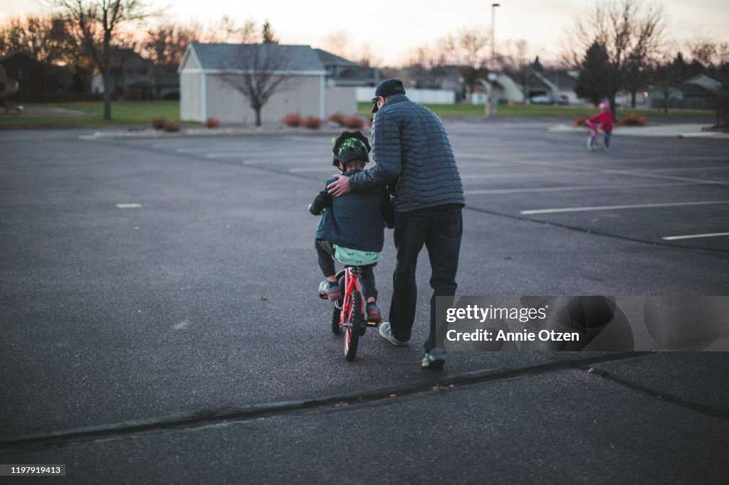 Man assisting a young boy ride a bike