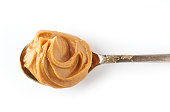 spoon of peanut butter isolated on white background, top view