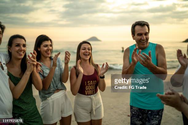 group of friends / family applauding at beach - parents applauding stock pictures, royalty-free photos & images