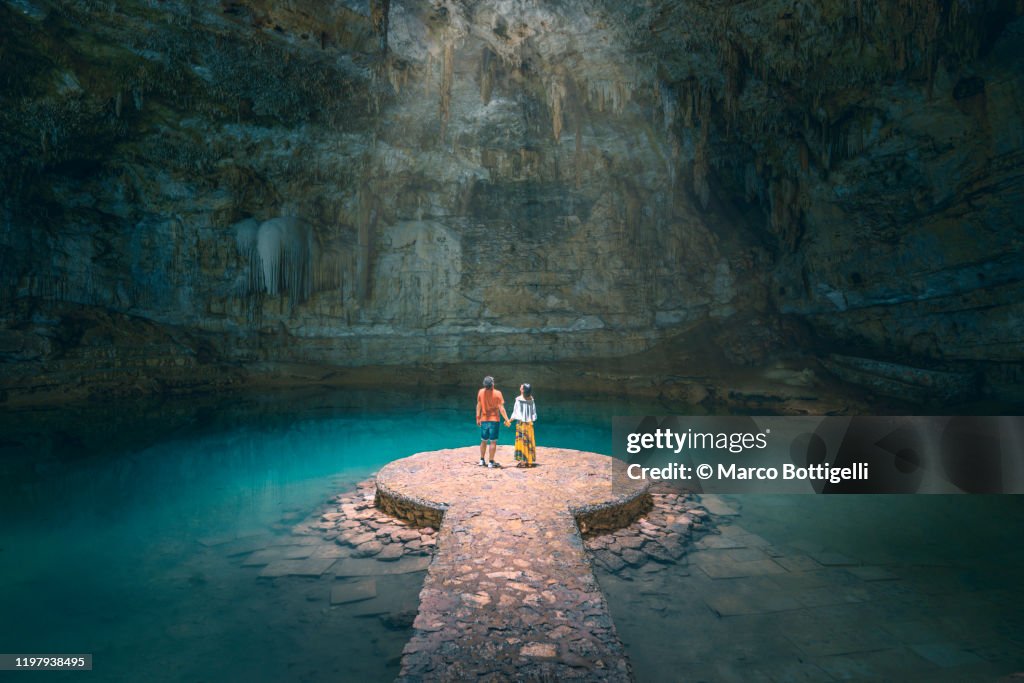 Couple holding hands exploring a cenote in Yucatan peninsula, Mexico