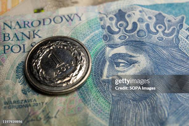 In this photo illustration a 1 zloty coin and 50 zlotys PLN banknote seen displayed.