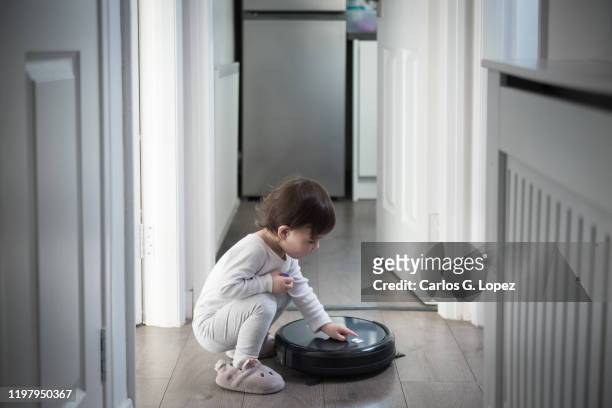 child switches on a robot vacuum in the corridor - play off stock pictures, royalty-free photos & images