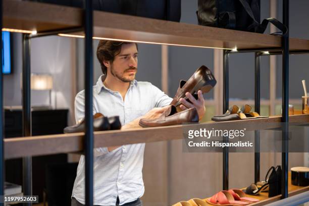 latinamerikansk ung man tittar på en formell sko på detaljhandeln display - latin american and hispanic shopping bags bildbanksfoton och bilder