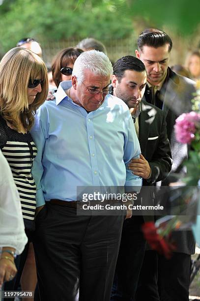 Amy Winehouse's father Mitch Winehouse brother Alex Winehouse and Amy's former boyfriend Reg Traviss look at floral tributes left at her house by...