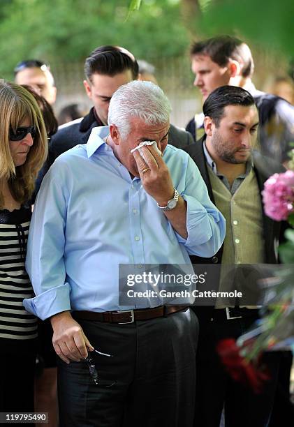 Amy Winehouse's father Mitch Winehouse and brother Alex Winehouse look at floral tributes left at her house by fans on July 25, 2011 in London,...