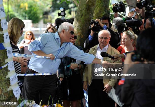 Amy Winehouse's father Mitch Winehouse greets a fan of his daughter as he looks at floral tributes left at her house by fans on July 25, 2011 in...