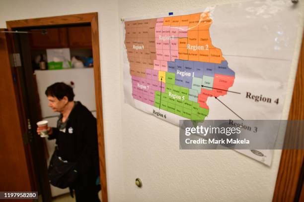 Volunteer walks with a cup of coffee past a map of Iowa divided in to targeted voter regions at a Bernie Sanders field office on February 1, 2020 in...