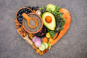 Heart shape of ketogenic low carbs diet concept. Ingredients for healthy foods selection on dark stone background. Balanced healthy ingredients of unsaturated fats for the heart and blood vessels.