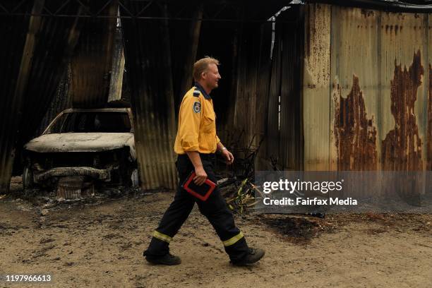 Rural Fire Service volunteers walk through the backyard of a property they saved from a bushfire, January 6, 2019. The surrounding sheds were...