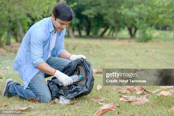 young man volunteer carrying garbage bags, garbage collection, cleaning in the public park. - garbage man stockfoto's en -beelden